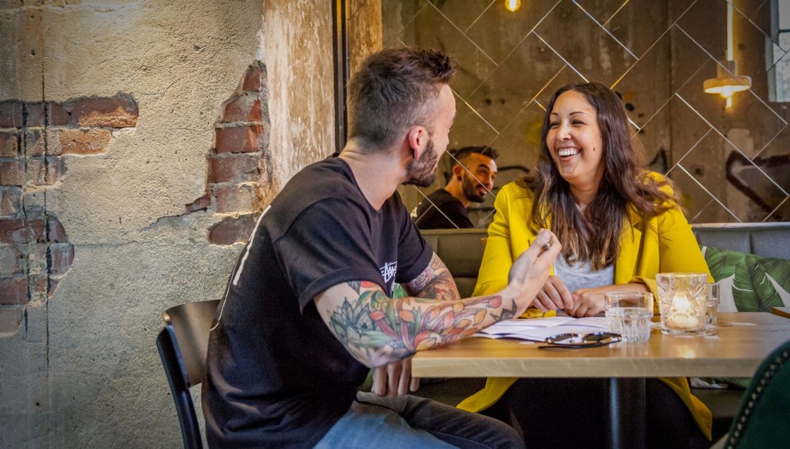 man en vrouw lachen aan tafel